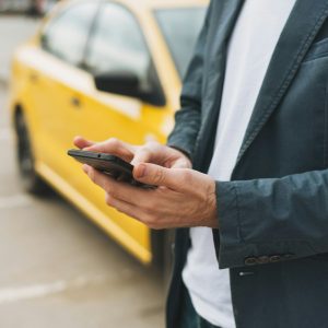 The man calls a taxi by app on his phone at street